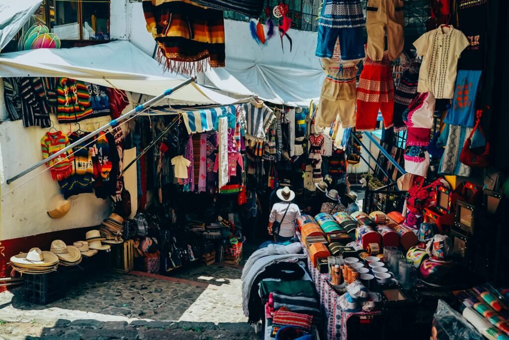 A bustling outdoor market stall showcasing traditional clothing and crafts in an inviting atmosphere.